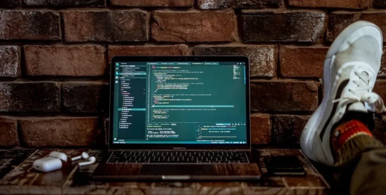 A laptop on a desk with some source code displayed on the monitor.